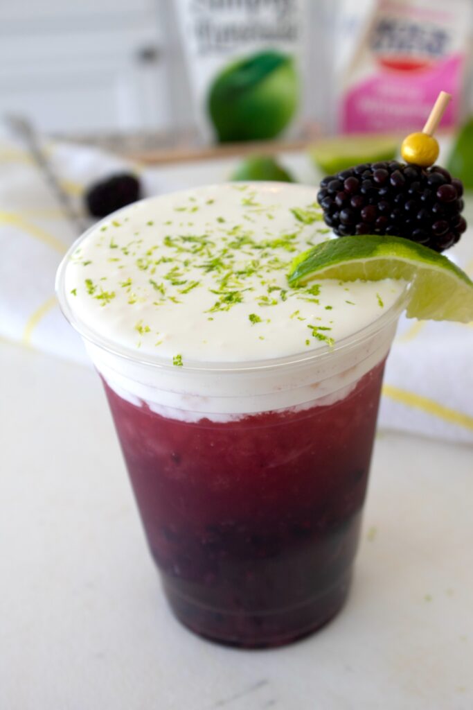 blackberry limeade in a to go cup with lime zest garnish