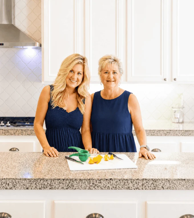 Kathi and Rachel Kirk in navy blue dresses in a white kitchen